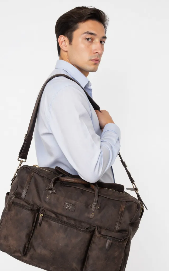 A French male model with a Travel bag with compartments, wearing a shirt, against a white background, in a front   facing close   up